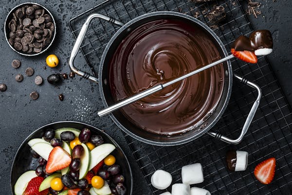 Topf mit geschmolzenem Schokoladen-Fondue und einer Schale mit Früchten