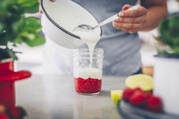 Joghurt wird aus einer Schale auf die pürierten Beeren gegeben.