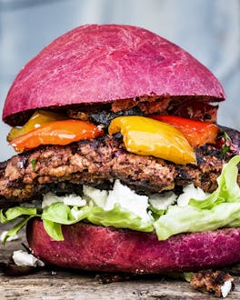 Burger mit Rindfleischpatty, Eisbergsalat und Grillgemüse in einem pinken Rote-Bete-Bun