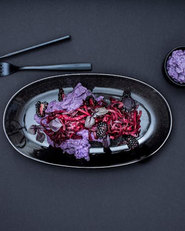 Möhren-Brombeer-Salat auf schwarzem ovalen Teller
