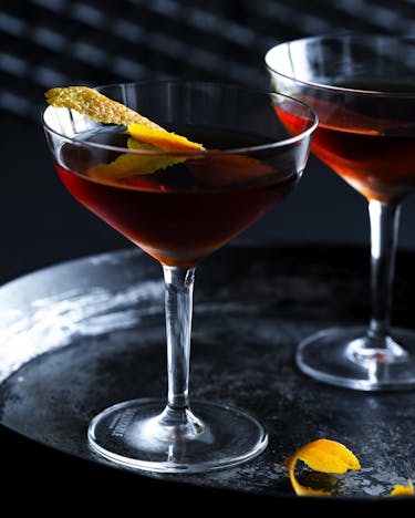 Tipperary Cocktail mit einer Orangenzeste in zwei Cocktailschalen.