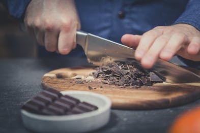 Schokolade wird auf einem Holzbrett gehackt