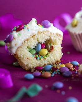 Cupcakes mit Smarties-Füllung auf pinkem Untergrund