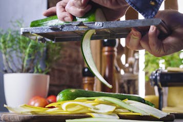 Zucchini werden für Gemüselasagne in Streifen geschnitten