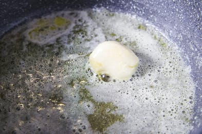 Knoblauchzehe wird in Butter angeschwitzt