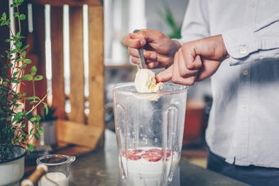 Erdbeeren und Milch werden im Standmixer mit Vanilleeis zum Milkshake verarbeitet.