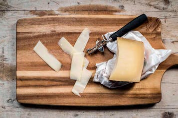Auf einem Holzbrett wird Käse geschnitten