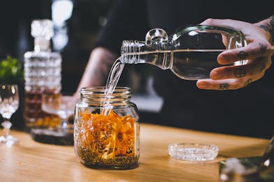Rum wird auf Orangenschale und Gewürze in einem Weckglas gegeben.