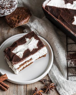 Angeschnittenes Lebkuchen-Tiramisu mit Kakao-Deko und Zimtstangen