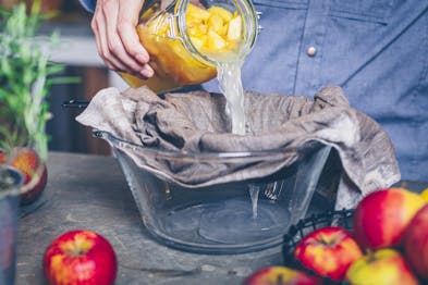Vergorene Äpfel werden in ein Küchentuch abgegossen für Apfelessig