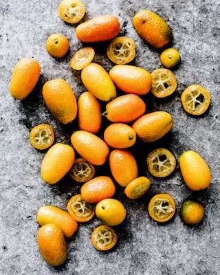 Kumquats ganz und aufgeschnitten auf grauem Untergrund