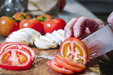 Tomaten in Scheiben schneiden, Mozzarella im Hintergrund