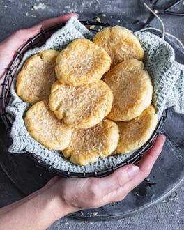 Parmesan-Cookies in Schale von 2 Händen gehalten
