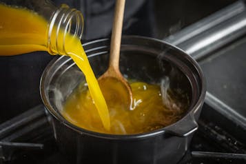 Karamellisierter Zucker wird in einem Topf mit Aprikosennektar abgelöscht.