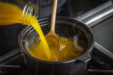 Karamellisierter Zucker wird in einem Topf mit Aprikosennektar abgelöscht.