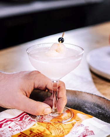 Litschi Martini Cocktail auf einem Silbertablett mit asiatischer Serviette.