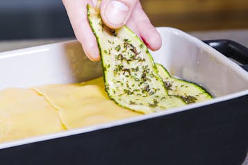 Zucchini wird auf Lasagneplatten gelegt für Gemüselasagne
