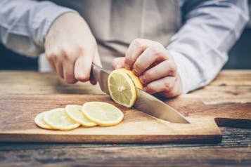 Zitronen werden auf einem Holzbrett in Scheiben geschnitten