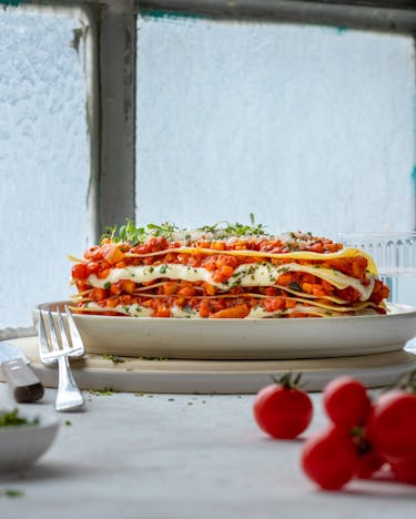 Geschichtete Lasagne mit Tomaten vor hellem Fenster