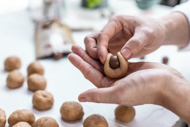 Hefeteig wird mit den Händen zu einer Kugel geformt und Schokolade eingearbeitet.