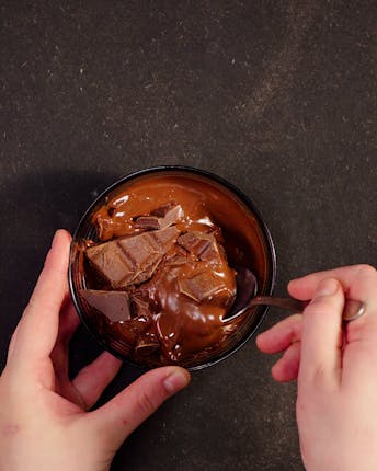 Halbflüssige Schokolade in einem Glas aus der Mikrowelle, die gerade umgerührt wird