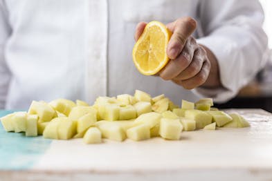 Zitrone wird über den Apfelwürfeln ausgepresst.
