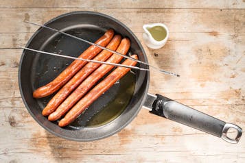 Für den Laugen-Hotdog mit Senfcreme: die Würstchen braten