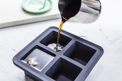 Espresso aus einer silber Kanne wird in eine Silikon-Eiswürfelform gegeben.