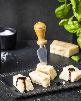 Parmesan-Keile mit Balsamico-Topping, im Parmesan steckt ein Messer