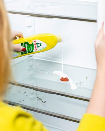 Jules reinigt mit einem Scheuermittel einen Ketchup-Fleck aus dem schmutzigen Kühlschrank