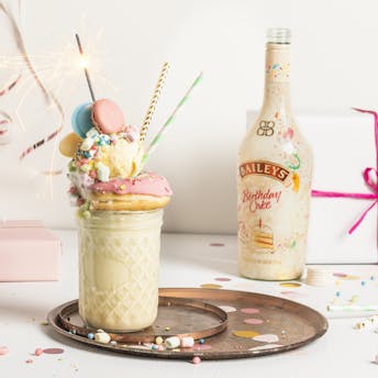 Bunter Baileys Birthday Cake Freakshake vor einem hellen Hintergrund mit Geschenken