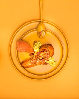 Ein Süßkartoffelkumpir mit Pfirsich Paprika Chutney auf orange-farbenen Teller sowie Hintergrund