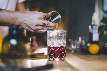 Barkeeper in Bar gibt Flüssigkeit aus Jigger in ein Tumbler