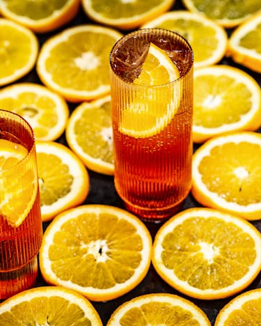 Zwei Gläser Aperol Spritz auf Untergrund aus Orangenscheiben