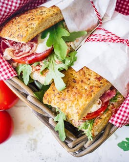Picknick-Sandwiches in Packpapier gewickelt in Korb angerichtet
