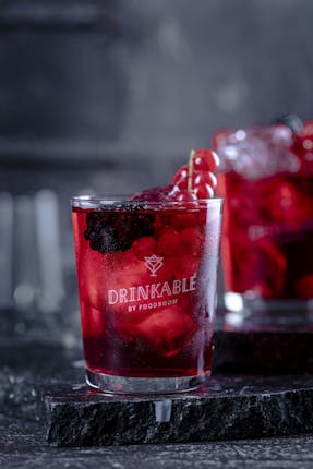 Zwei Gläser mit einem roten Drink und verschiedenen Beeren darin