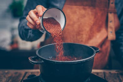 In einen schwarzen Topf wird roter Quinoa geschüttet