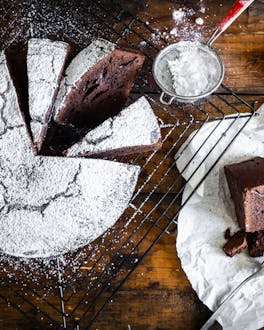 Italienischer Schokoladenkuchen mit Puderzucker auf dunklem Holzuntergrund
