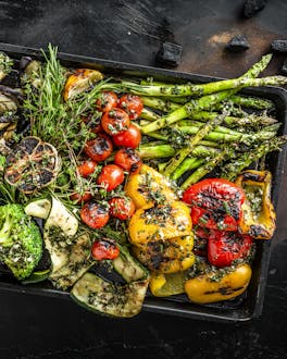 Eine bunte vegane Grillplatte mit gemischtem gegrillten Gemüse: Brokkoli, Kirschtomaten, Aubergine, Zucchini, grüner Spargel  und Paprika