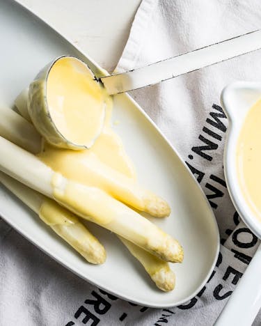 Schnelle selbst gemachte Sauce Hollandaise mit Butter, Ei und Weißwein zu weißem Spargel.