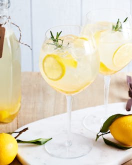 2 Gläser alkoholfreier Limoncello Spritz, daneben Zitronen