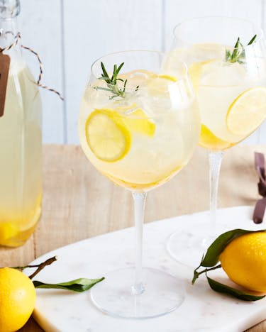 2 Gläser alkoholfreier Limoncello Spritz, daneben Zitronen