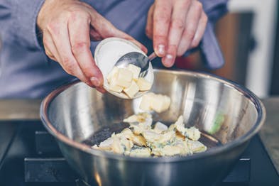 Gestückelte Butter wird zu gerupften Gorgonzola in einer Pfanne gegeben