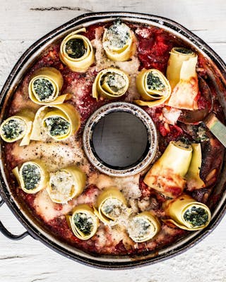 Aufgerollte Lasagneplatten gefüllt mit Spinat hochkant in eine Springform mit Loch gestellt, dazu Tomatensauce und Käse