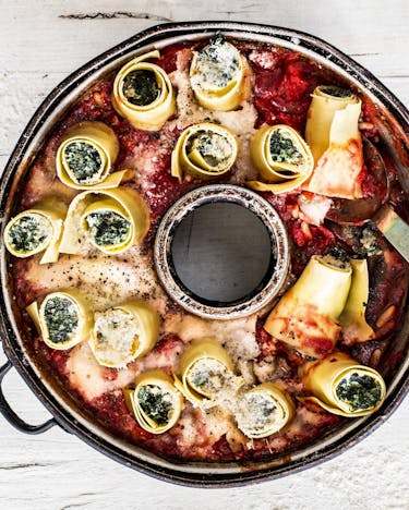 Aufgerollte Lasagneplatten gefüllt mit Spinat hochkant in eine Springform mit Loch gestellt, dazu Tomatensauce und Käse
