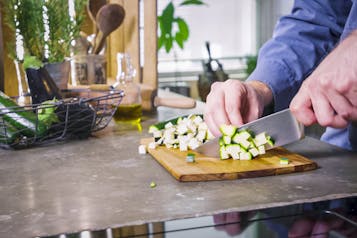 Zucchini werden für vegetarische Mini-Calzoni gewürfelt
