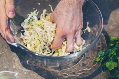 Kohl wird in einer Schüssel für den Krautsalat mit Speck massiert