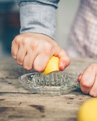 Eine halbe Zitrone wird in einer Saftpresse ausgedrückt