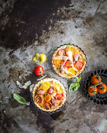 Mini-Quiches mit Tomaten, Basilikum und Parmesan auf dunkle, Untergrund