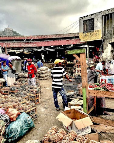 Der Mercado de Bazurto: Viele Ananasfrüchte aufgestapelt auf einem Markt. Dazwischen stehen Menschen.